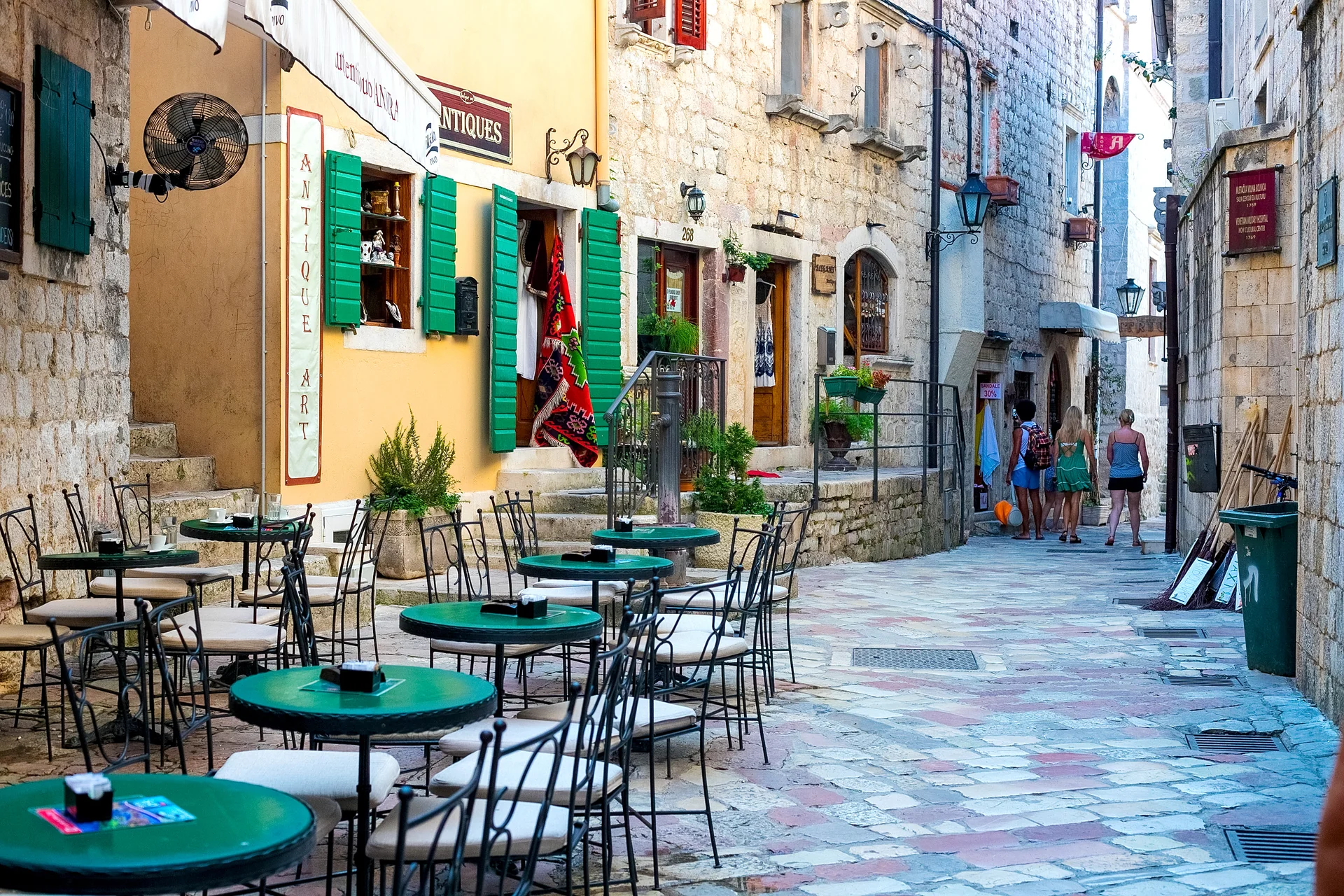 Outdoor konoba restaurant in Kotor Old Town with tables set under yellow umbrellas